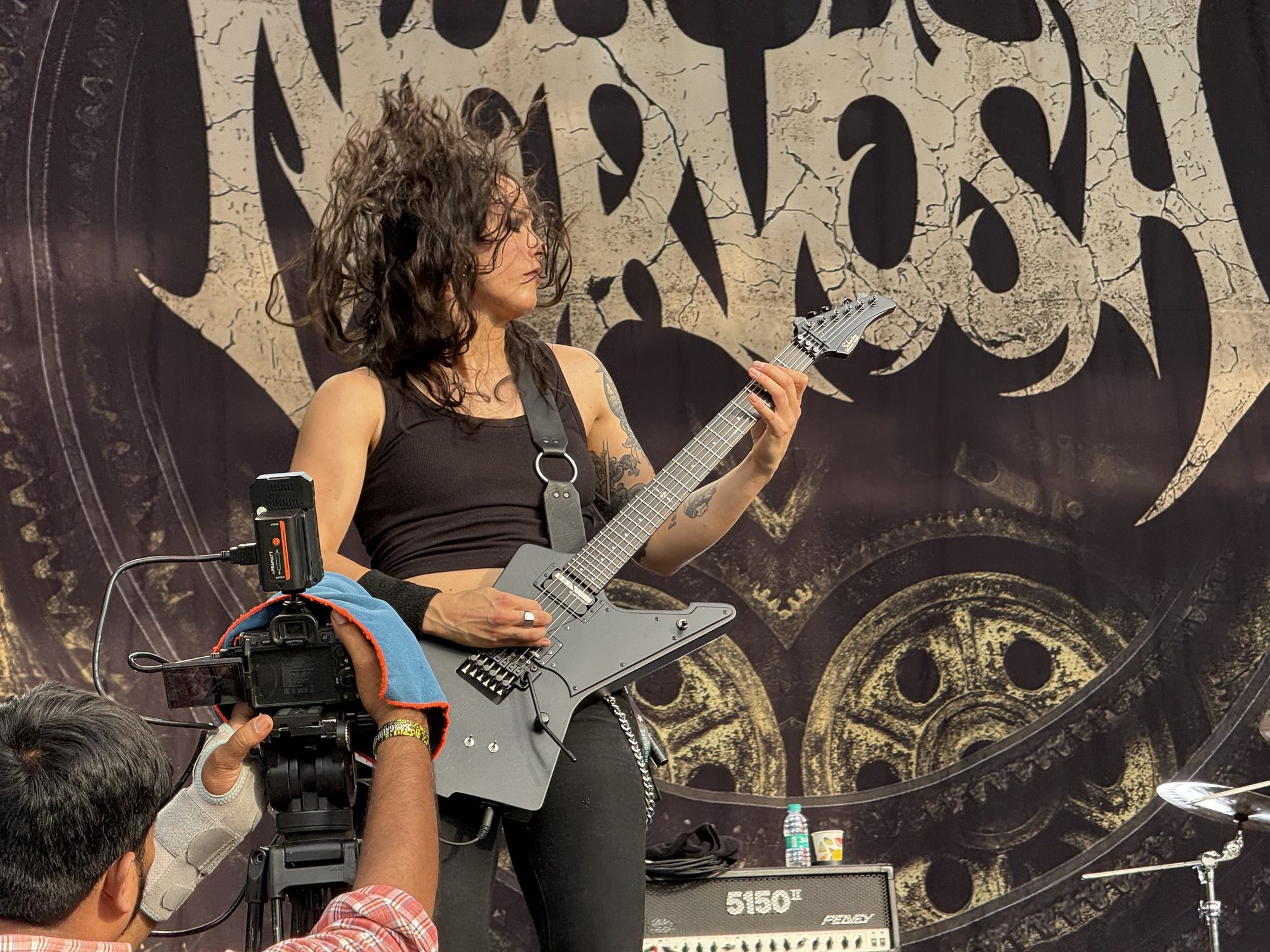 Nervosa guitarist in front of the band’s banner